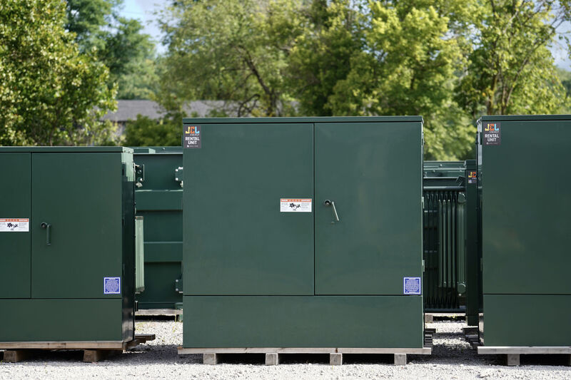 Green metal storage containers with trees in the background