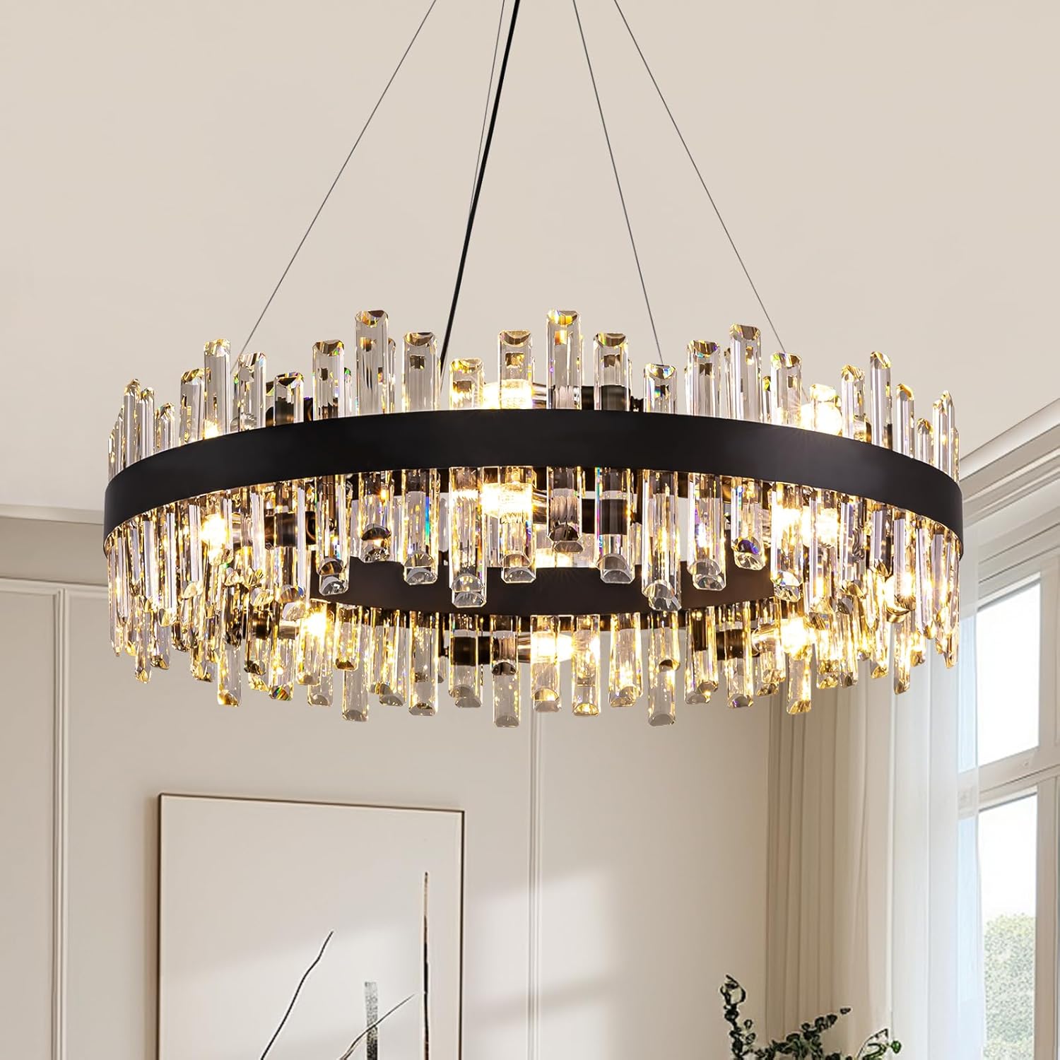 Chandelier with crystal accents hanging in a room with a window and framed picture on the wall.