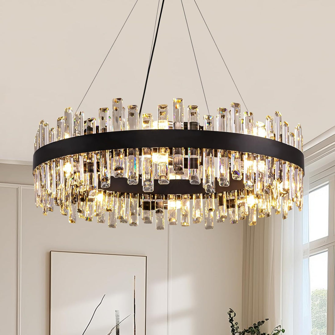 Chandelier with crystal accents hanging in a room with a window and framed picture on the wall.