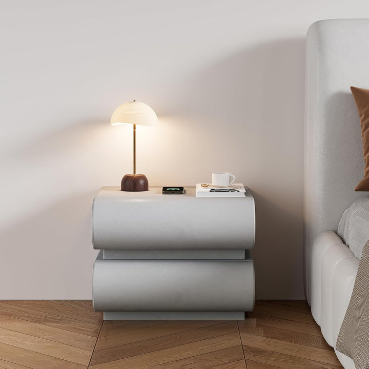 Modern nightstand with lamp and cup next to a bed in a bedroom setting