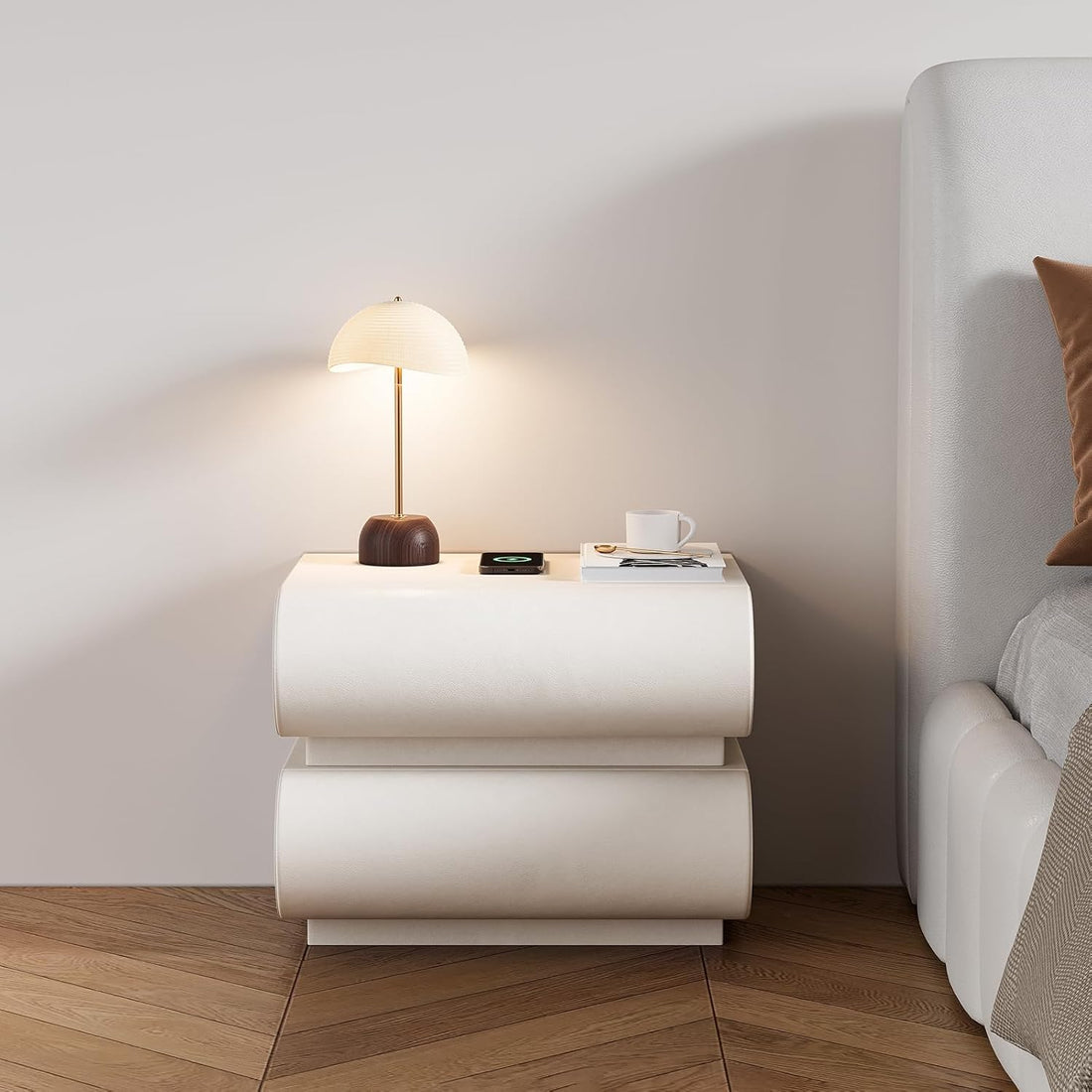 White nightstand with lamp and cup next to a bed in a bedroom.