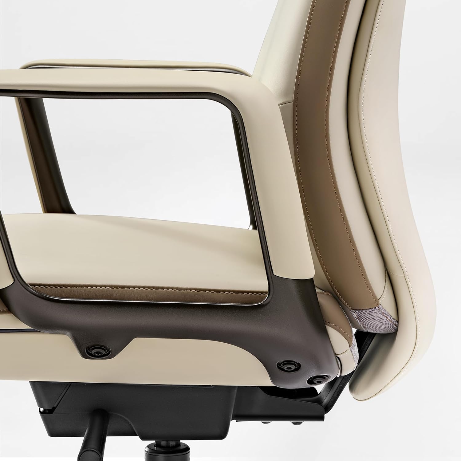 Close-up of a modern office chair showing the side profile of the seat, armrest, and backrest. The chair features cream and tan leather upholstery with dark brown structural accents and a black base.