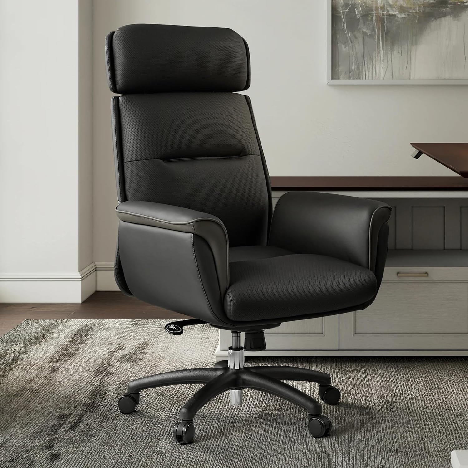 Black office chair in a room with a desk and abstract painting.