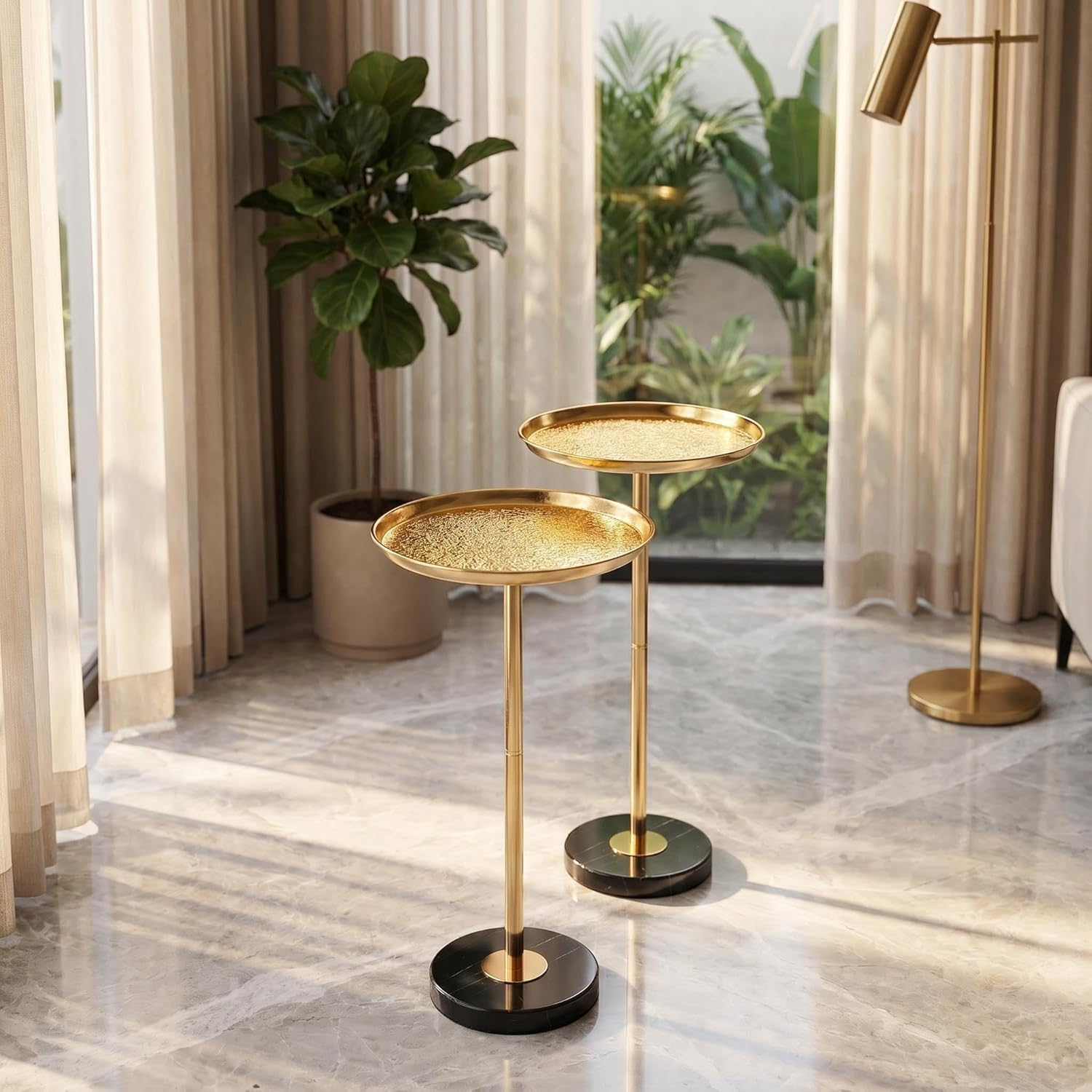 Gold side table with two round shelves in a room with curtains and plants