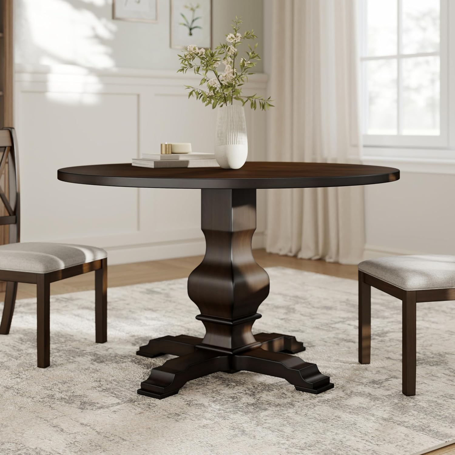 Round wooden dining table with two chairs in a room with light-colored walls and a window.