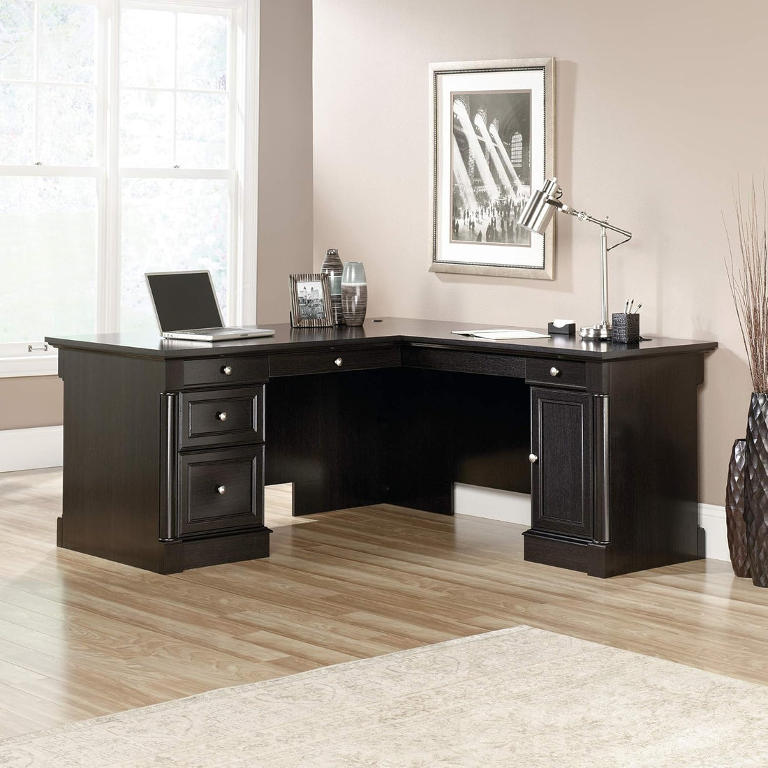 Black L-shaped desk in a home office setting with decor elements.
