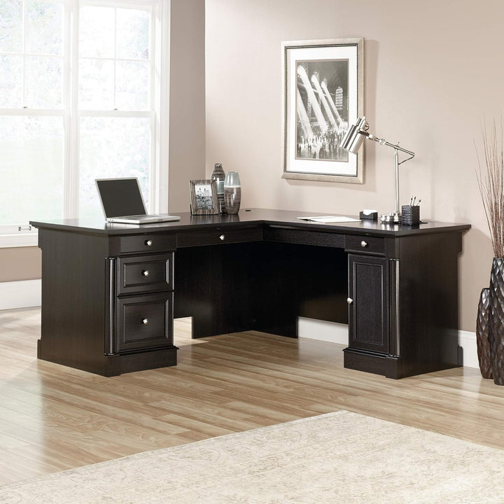 Black L-shaped desk in a home office setting with decor elements.