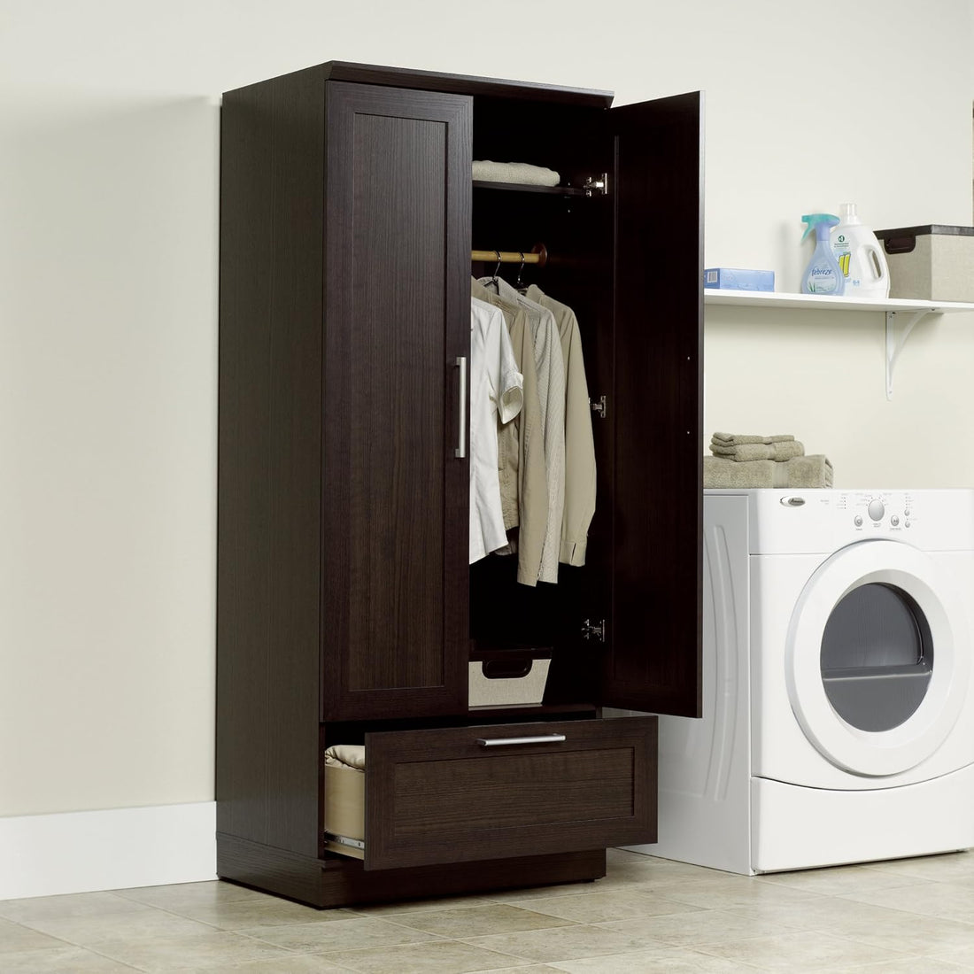 Wooden wardrobe with open doors in a laundry room with a dryer.