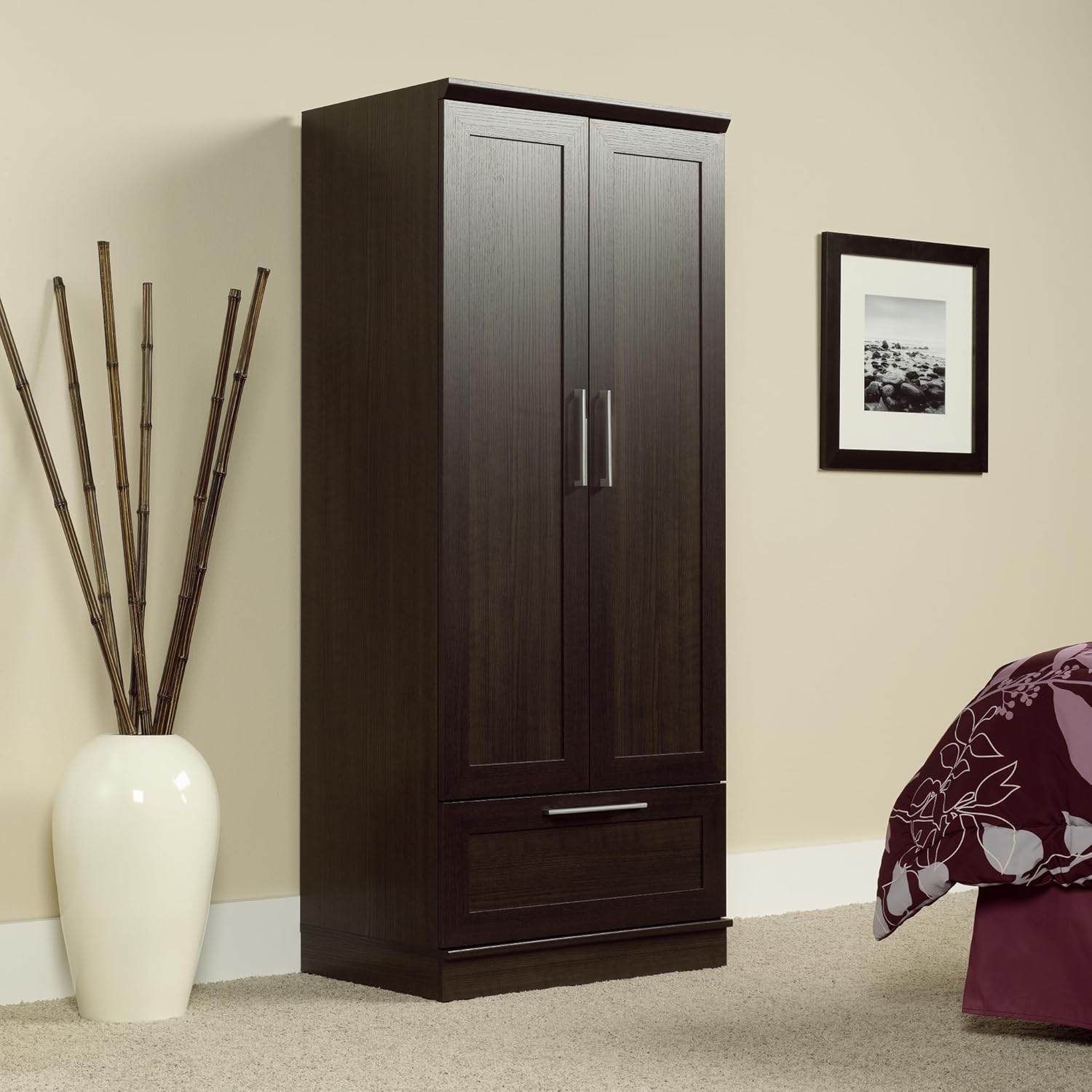 Dark wood wardrobe with a white vase and decorative plant in a room.