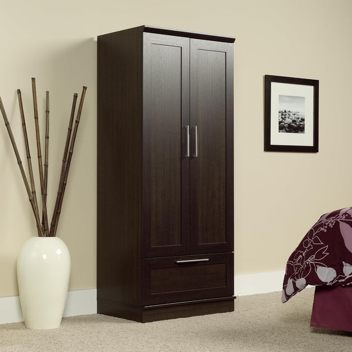 Dark wood wardrobe with a white vase and decorative plant in a room.