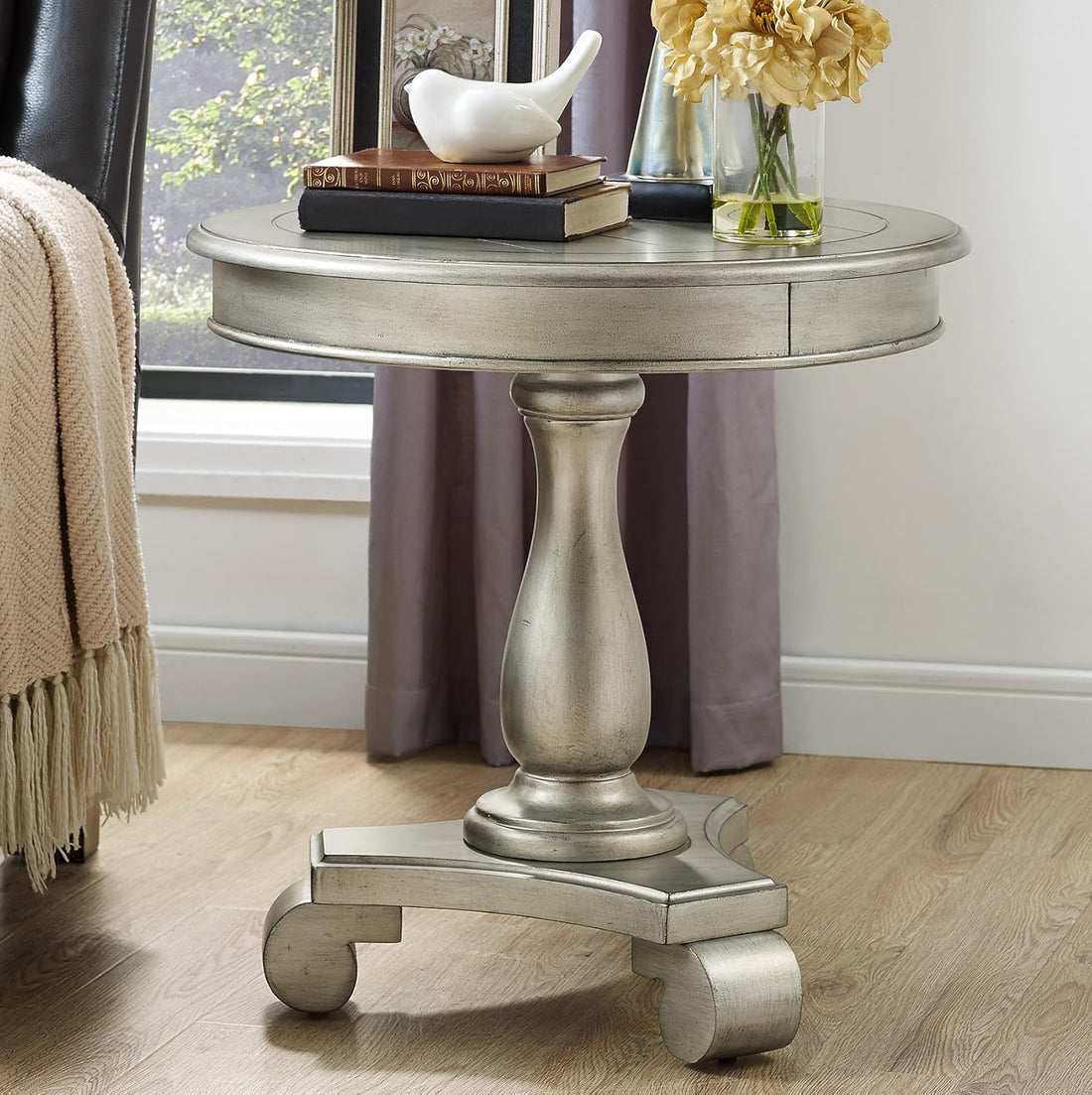 Round silver side table with decorative items in a room setting