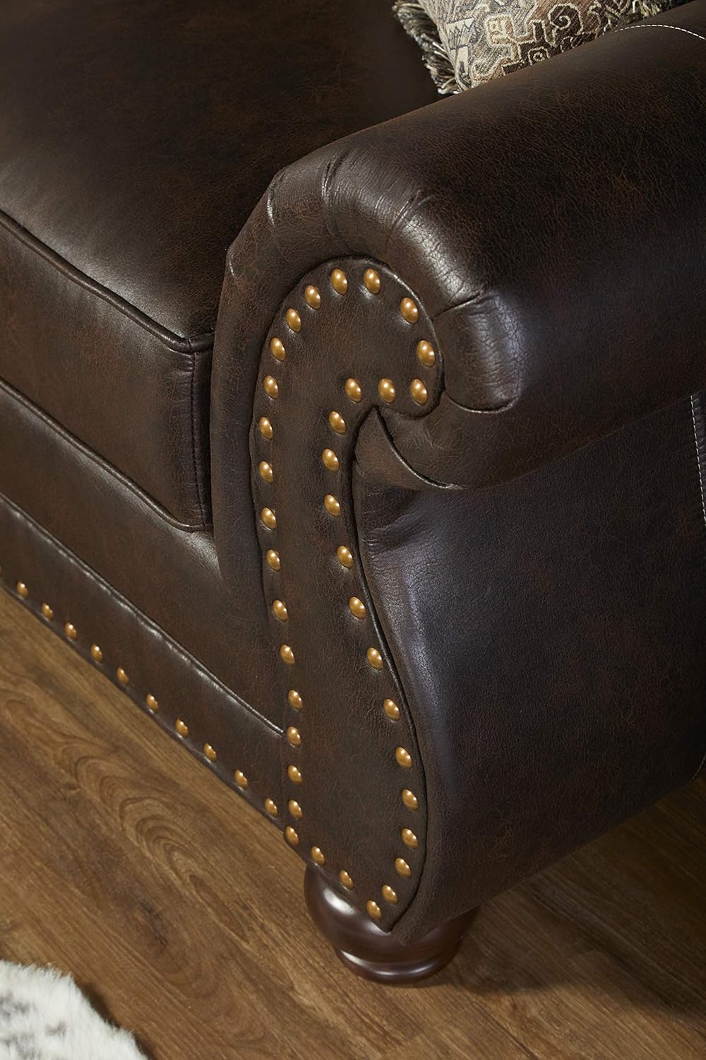 Brown leather armchair with studded details on a wooden floor