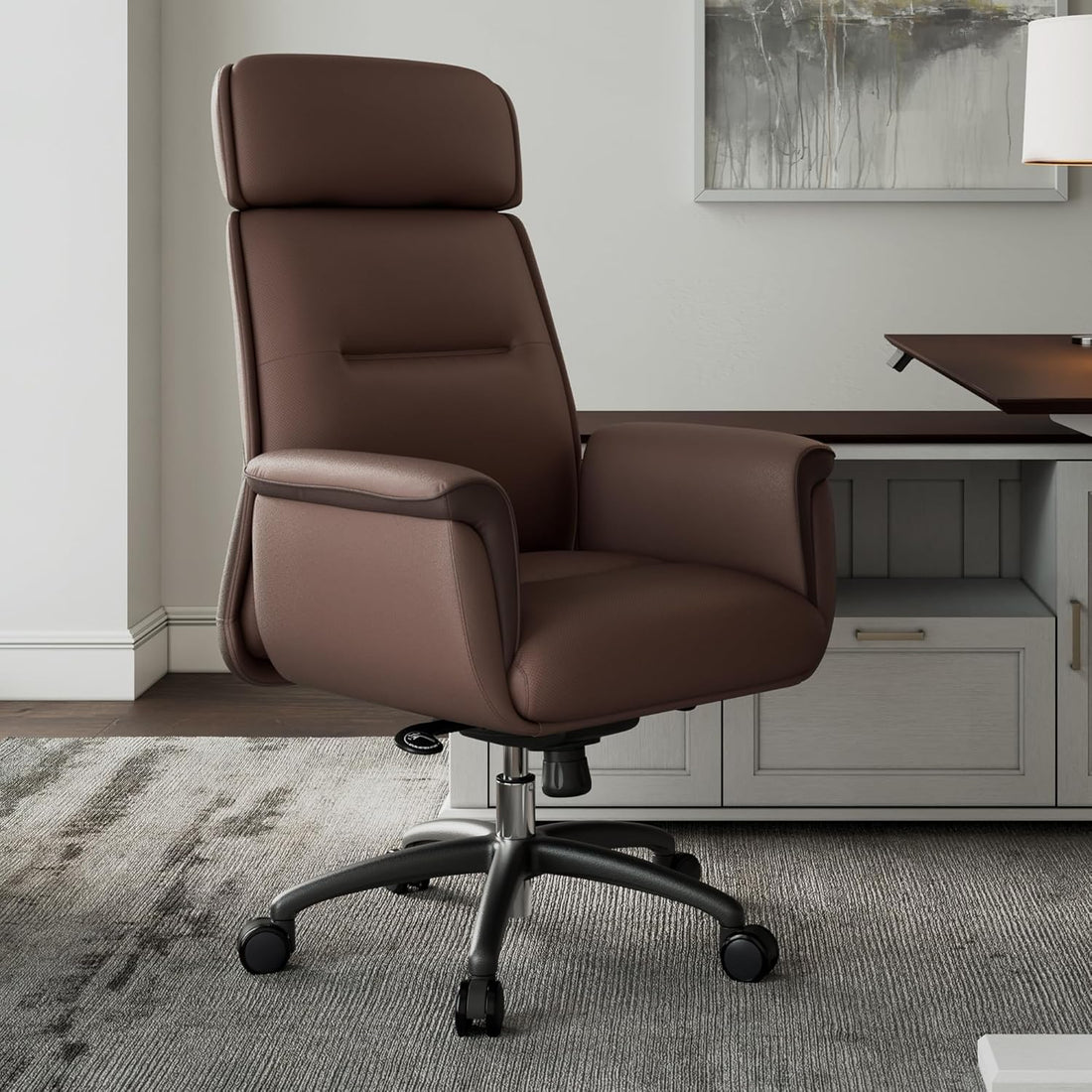 Brown office chair in a home office setting with a desk and artwork on the wall.