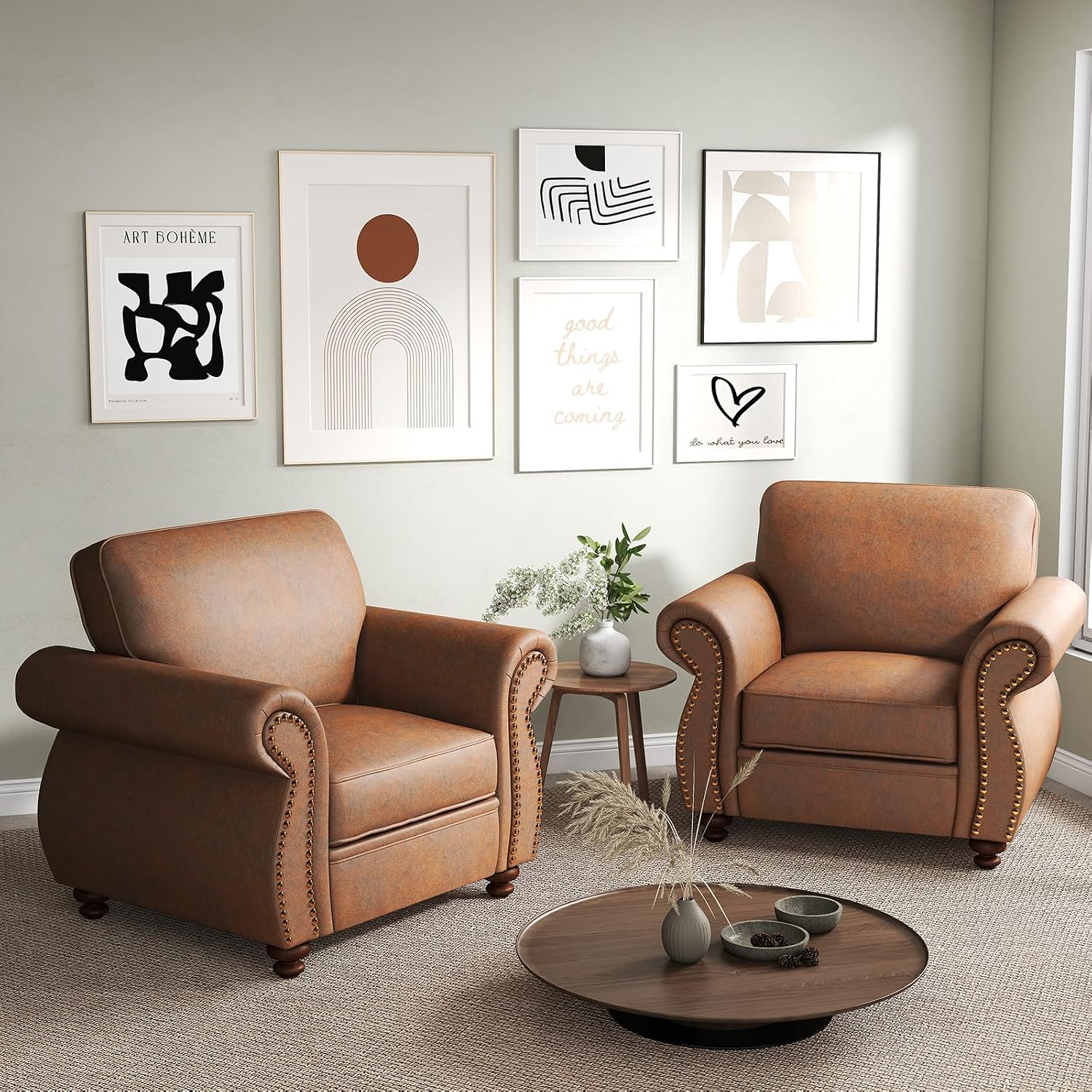 Two brown leather armchairs in a styled living room setting with a round coffee table, a small side table with a plant, and six framed abstract art prints on a light sage green wall.