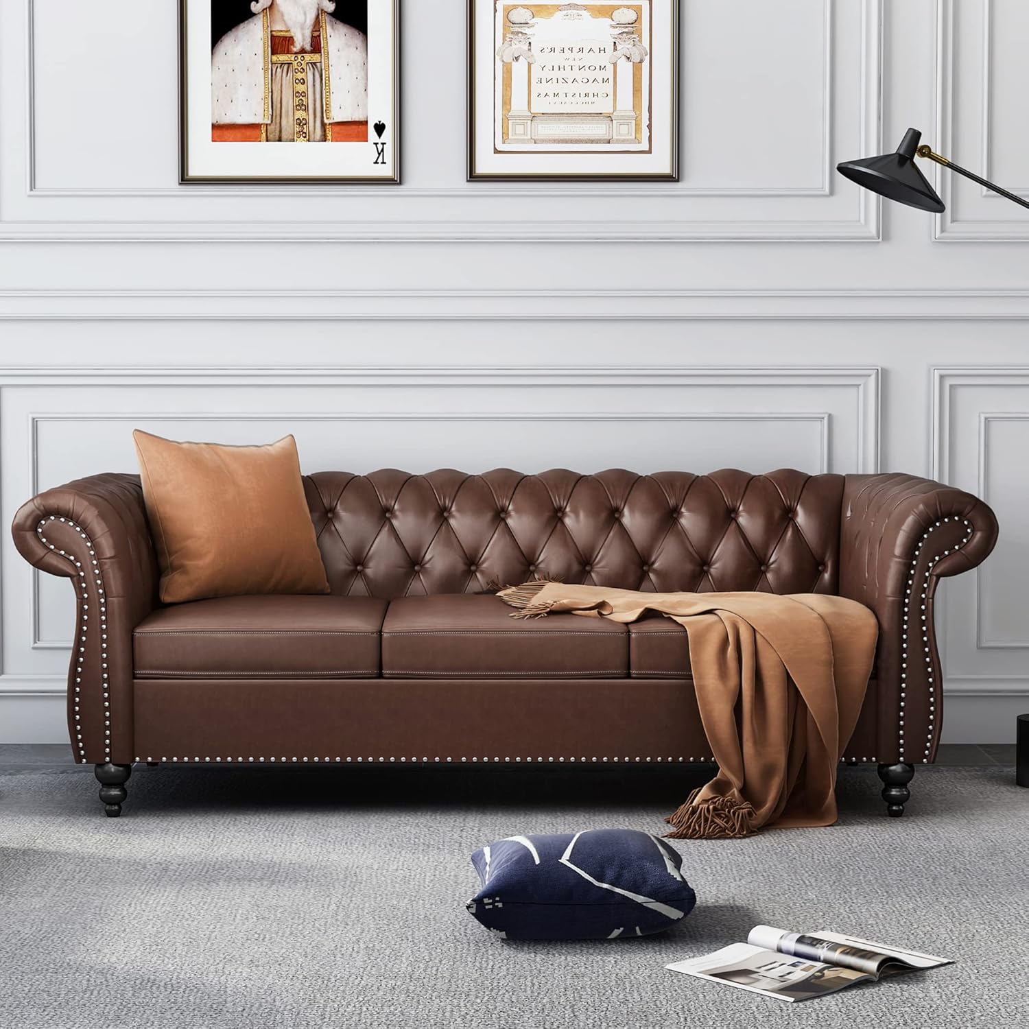 Brown leather sofa in a living room with decorative pillows and a blanket.