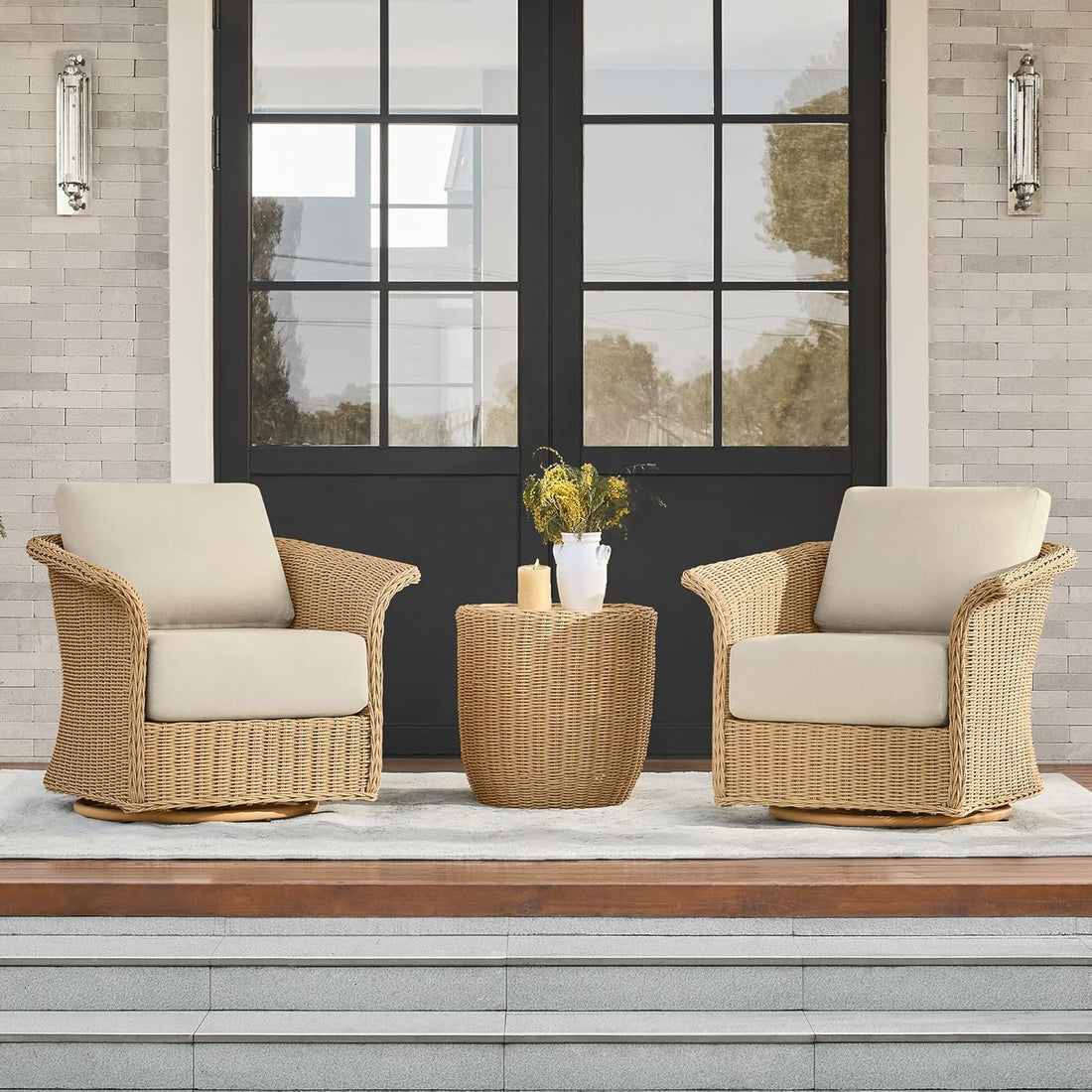 Two wicker chairs with beige cushions and a matching table on a patio.