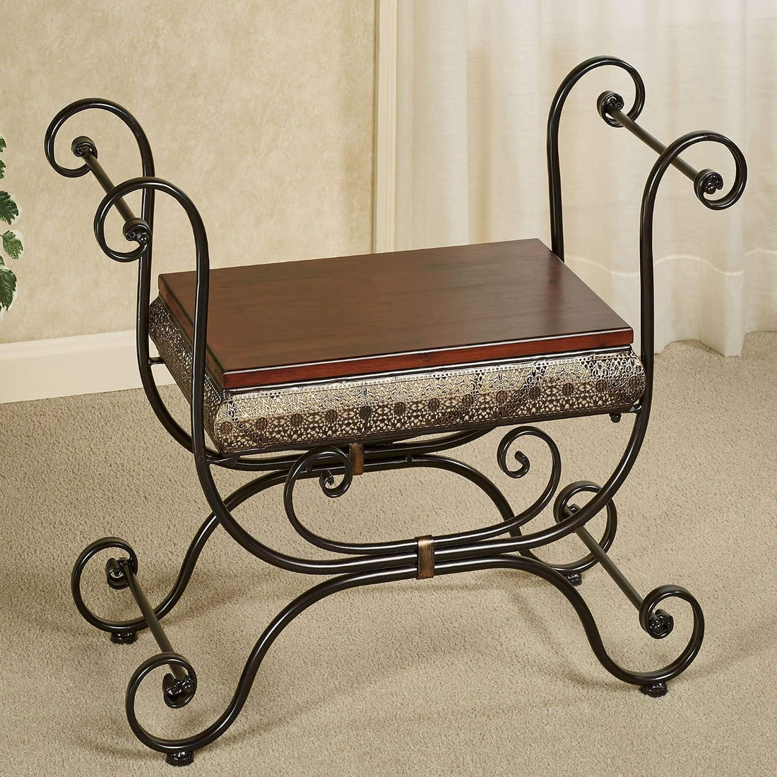 A wrought iron bench with a dark brown wooden seat and a patterned fabric cushion, set on a beige carpeted floor in front of a cream curtain.