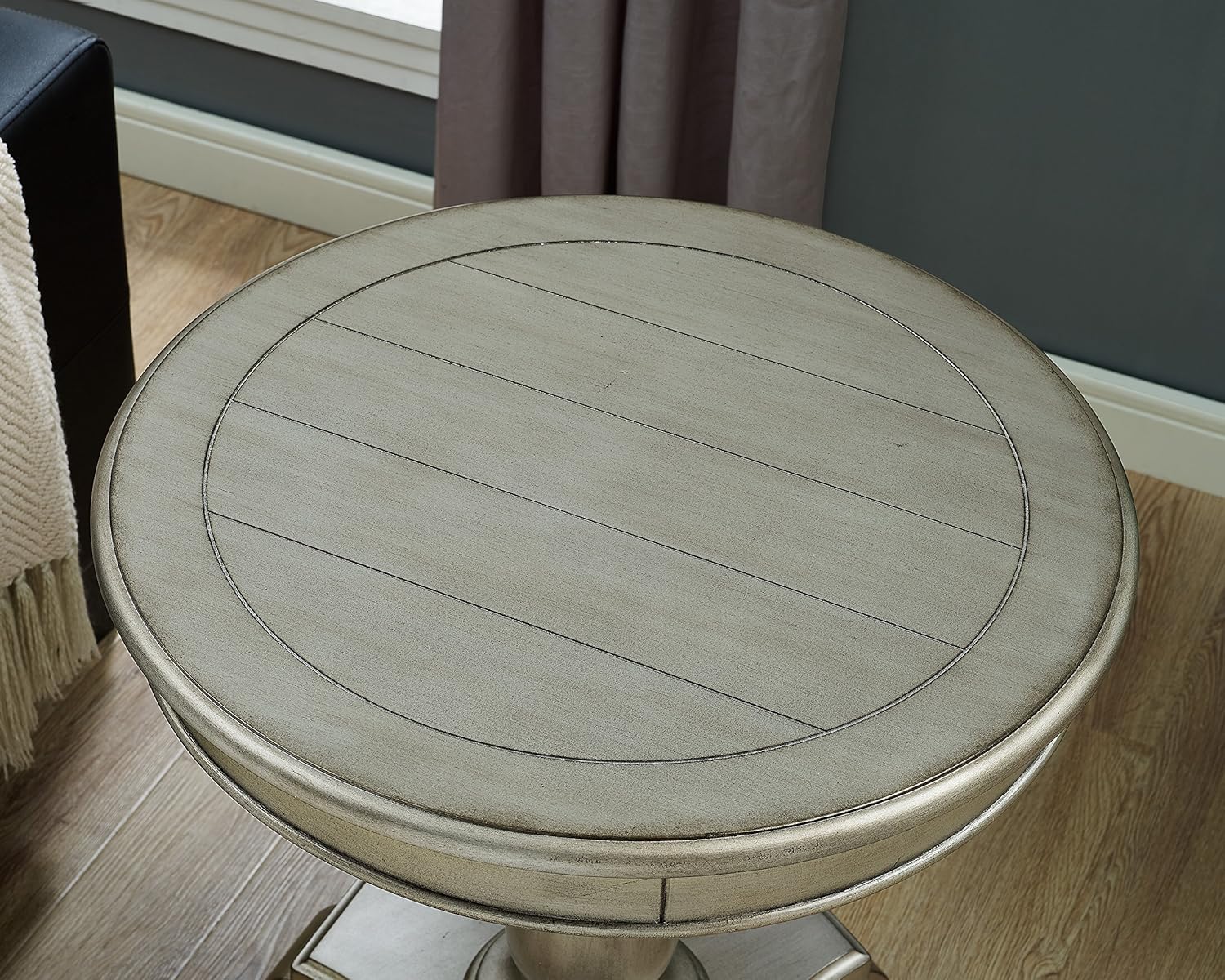 Round wooden table with a textured surface in a room setting.