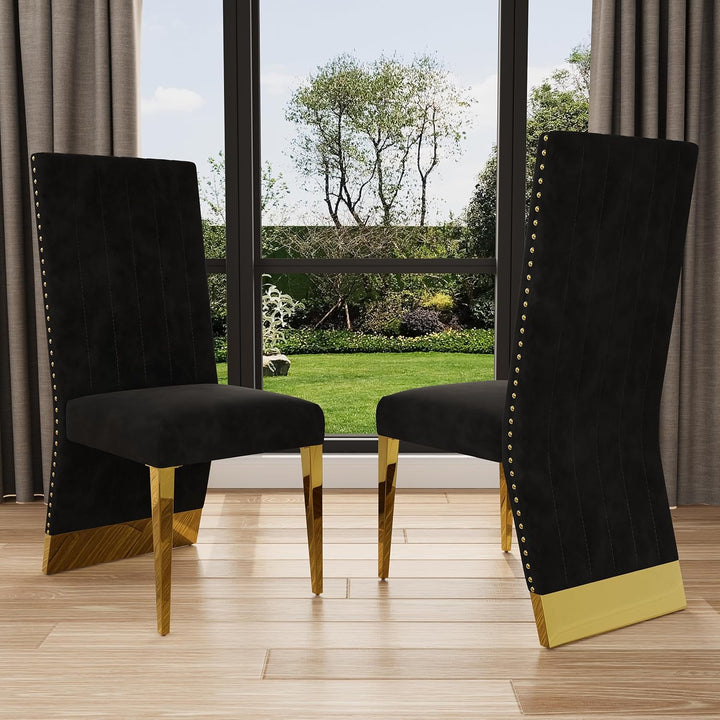 Two black upholstered chairs with gold legs in a room with large windows showing a garden view.