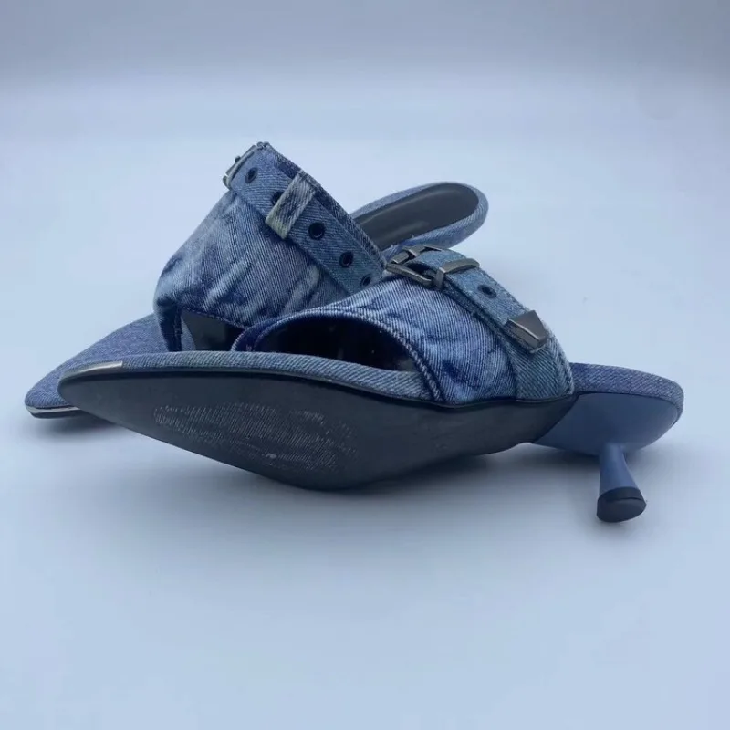 A pair of women's heeled sandals made from blue denim, featuring pointed toes, open straps with decorative buckles, and a low block heel, shown on a light gray background.