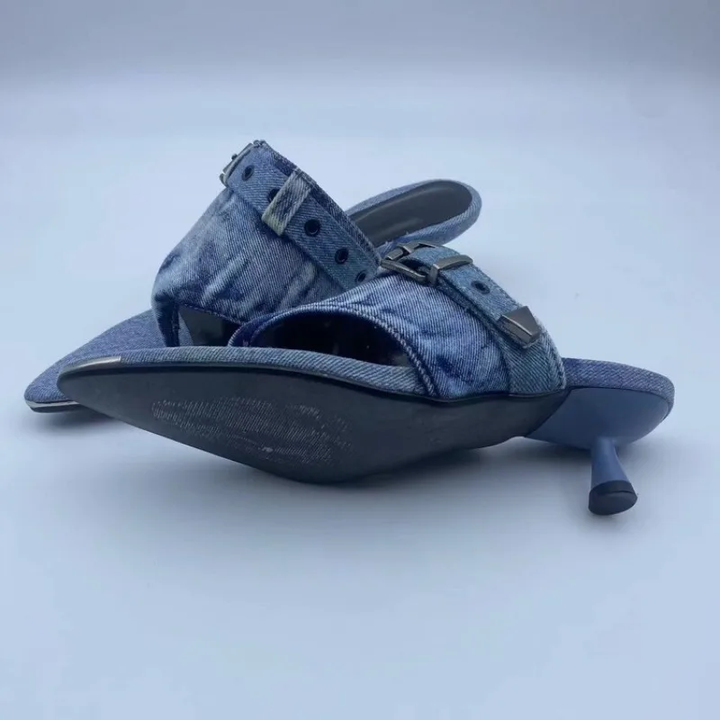 A pair of women's heeled sandals made from blue denim, featuring pointed toes, open straps with decorative buckles, and a low block heel, shown on a light gray background.