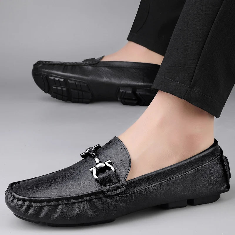 Black leather loafers worn with black pants on a gray background