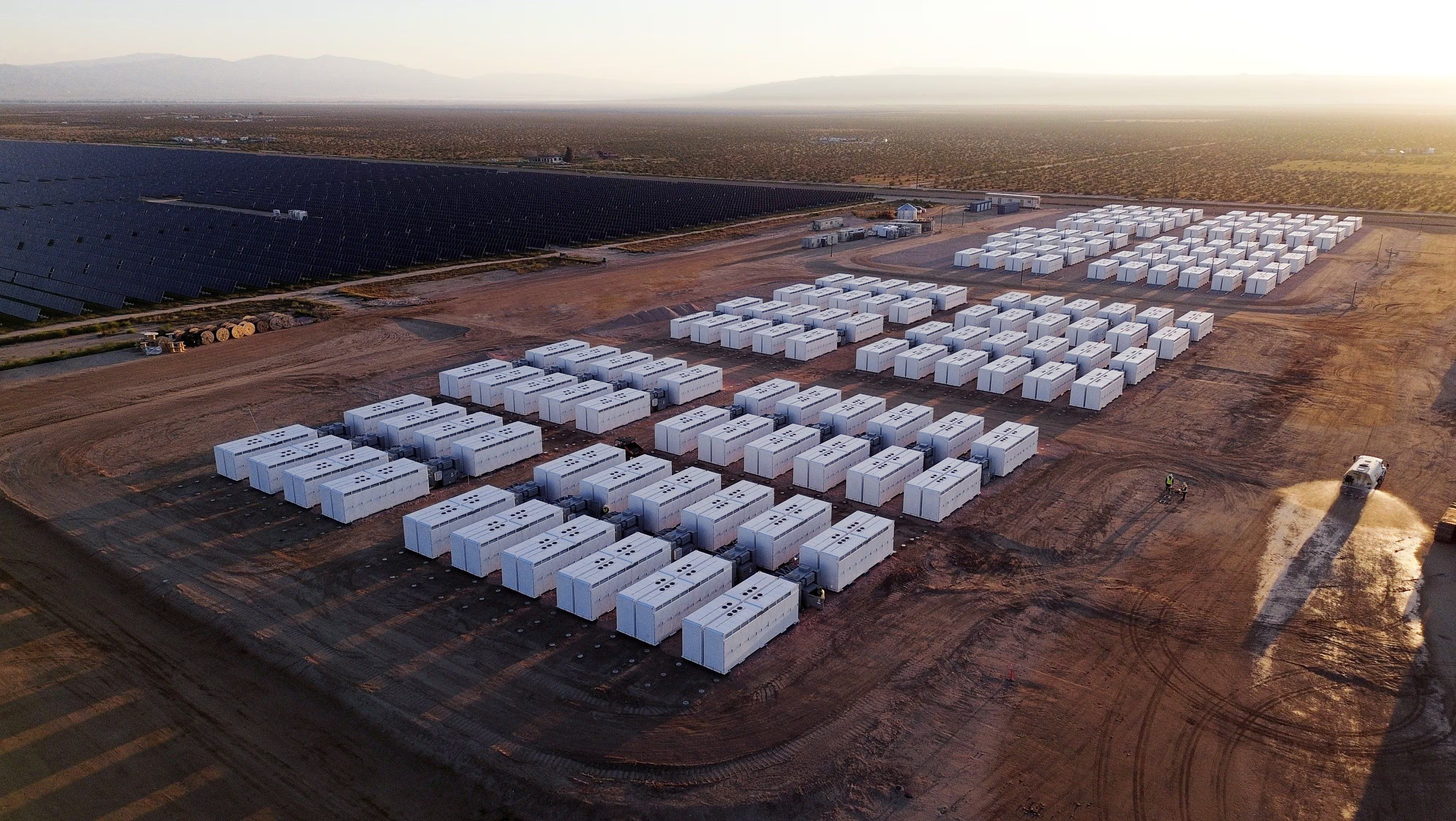 Large battery storage facility with solar panels in the background
