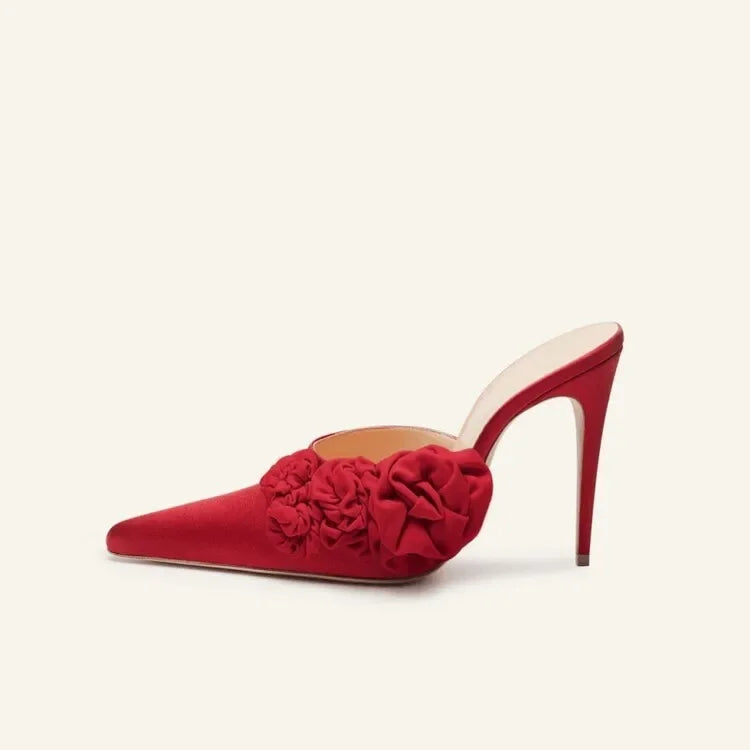 A single red pointed-toe mule high heel with a large 3D fabric flower embellishment on the vamp, shown against a solid off-white background.