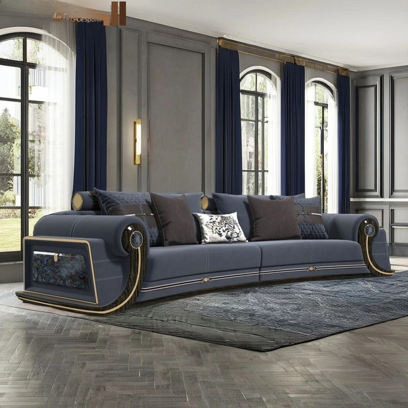 A luxury curved sofa in slate blue with gold trim and dark brown cushions, styled in a grand room with tall windows, navy curtains, and a gray rug.