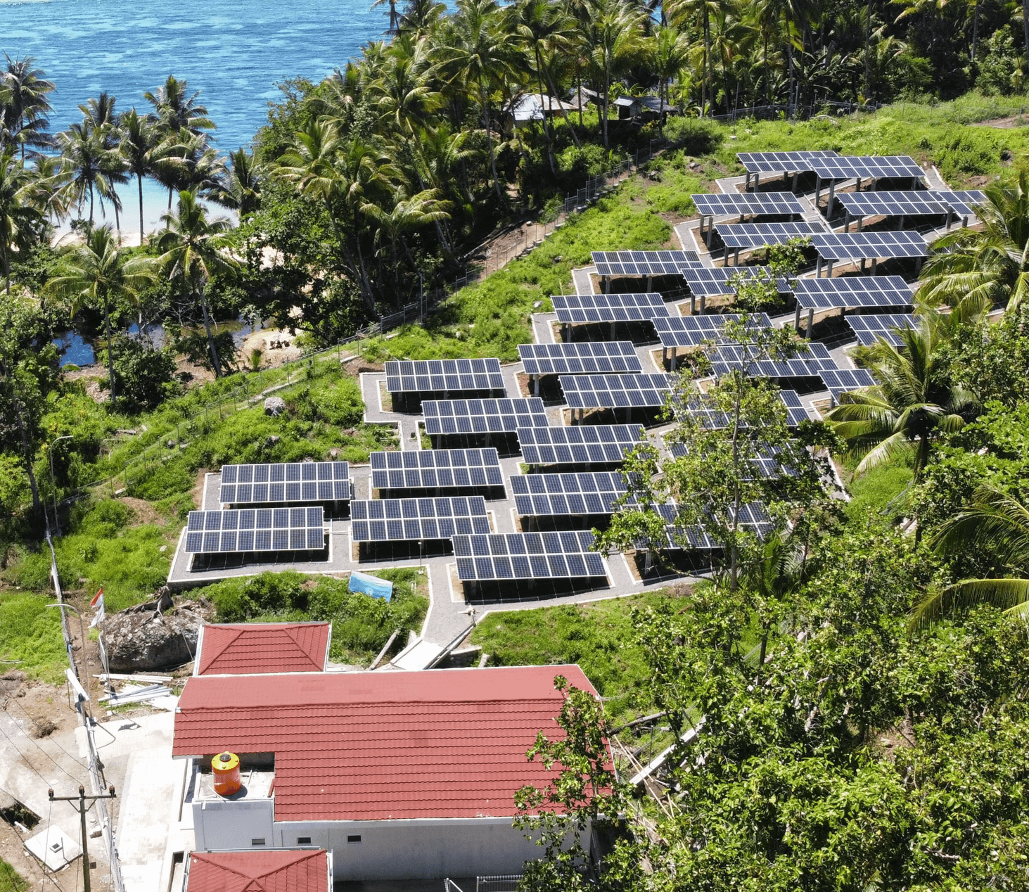 Row of solar panels on a grassy area with a house and ocean in the background