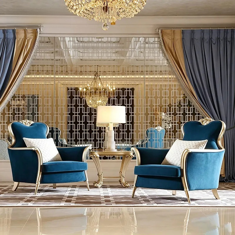 Luxurious living room with blue armchairs, gold accents, and a chandelier.