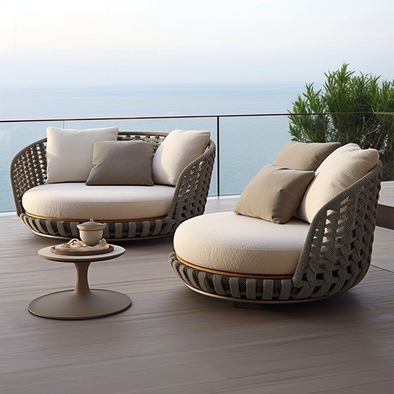 Modern outdoor furniture set with wicker chairs and cushions on a deck with ocean view.