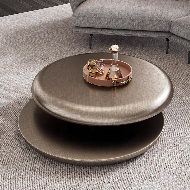 Round metallic coffee table with a tray holding drinks in a living room setting.