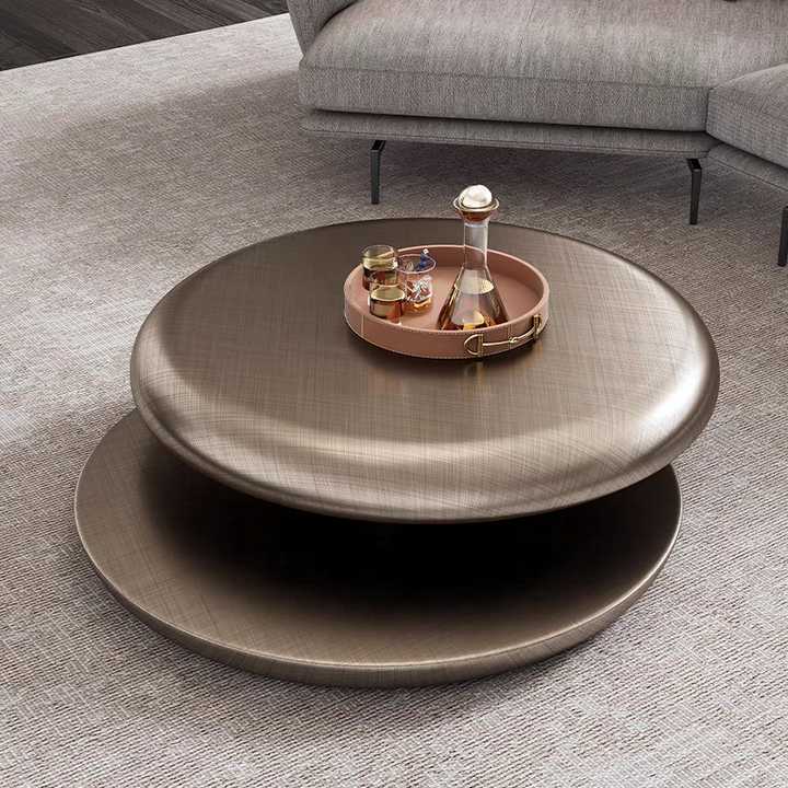 Round metallic coffee table with a tray holding drinks in a living room setting.