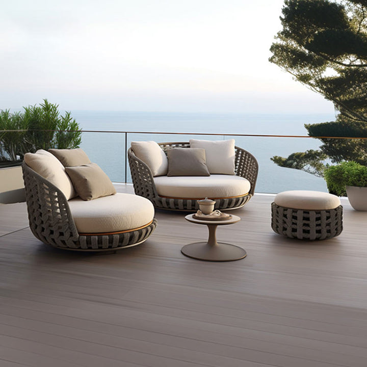 Outdoor patio set with chairs, ottoman, and table on a wooden deck with ocean view.