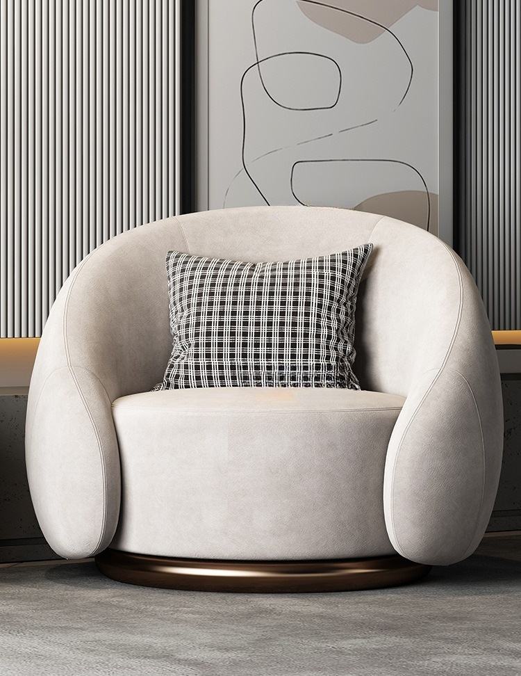 Beige armchair with a plaid pillow in a room with abstract art on the wall.