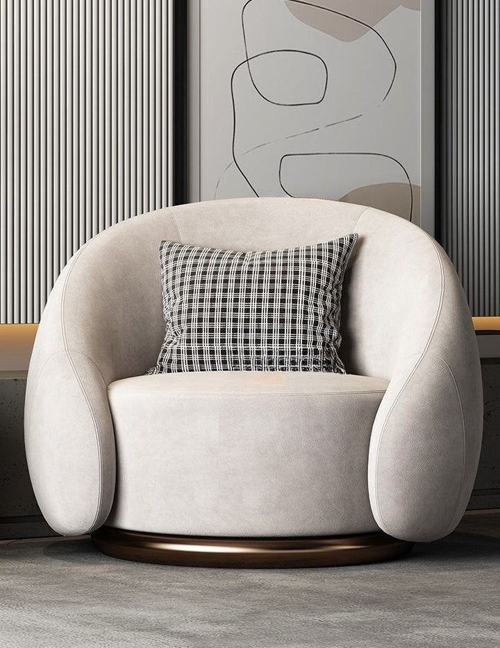 Beige armchair with a plaid pillow in a room with abstract art on the wall.