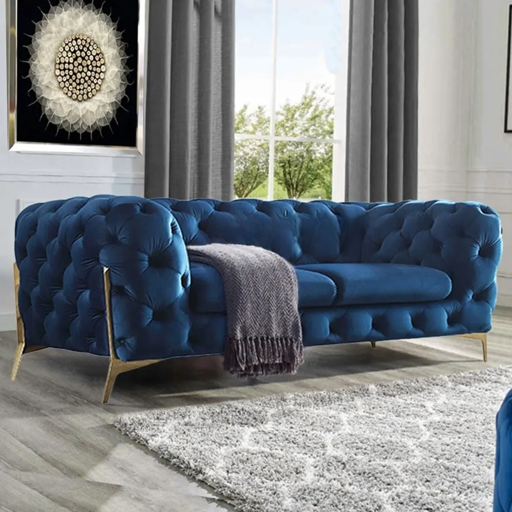 Blue tufted sofa in a living room with a gray rug and large window.