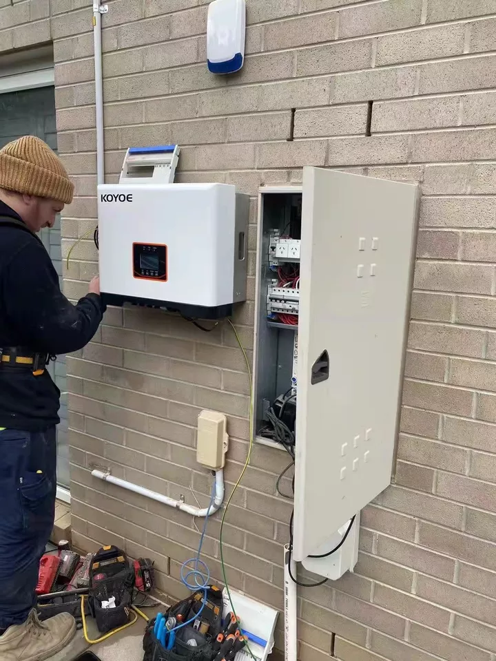 Person working on an electrical panel mounted on a brick wall