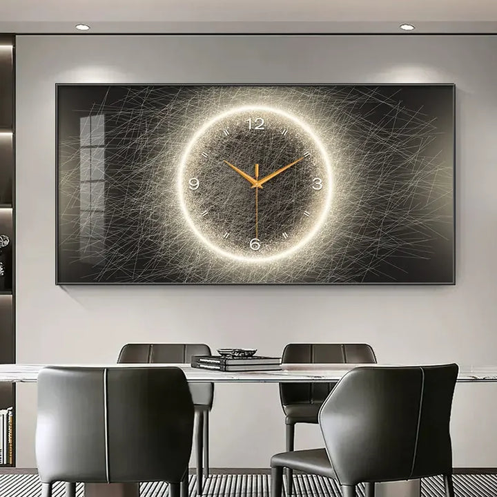A large rectangular wall clock with a glowing circular design and gold hands, mounted above a dining table with dark chairs in a modern room.