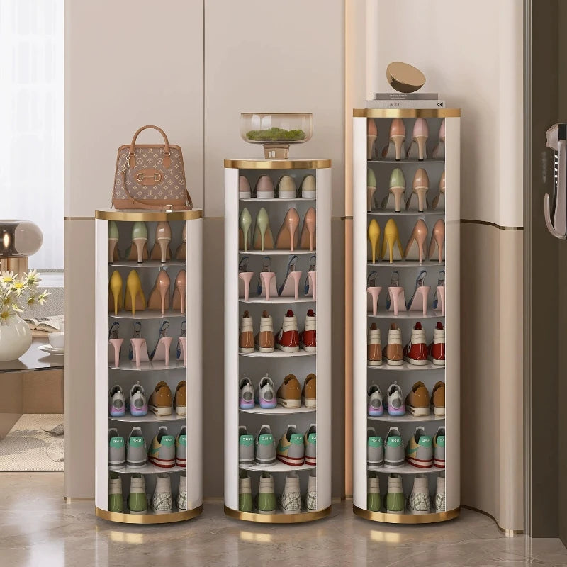 Three slim cylindrical shoe storage racks with gold trim and glass doors, filled with assorted shoes, shown in a modern beige entryway. A brown handbag sits on the left rack and a small bowl is on the center rack.