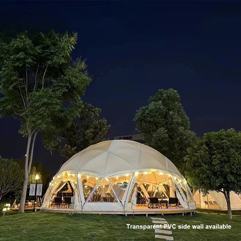 Geodesic dome tent with lights at night surrounded by trees
