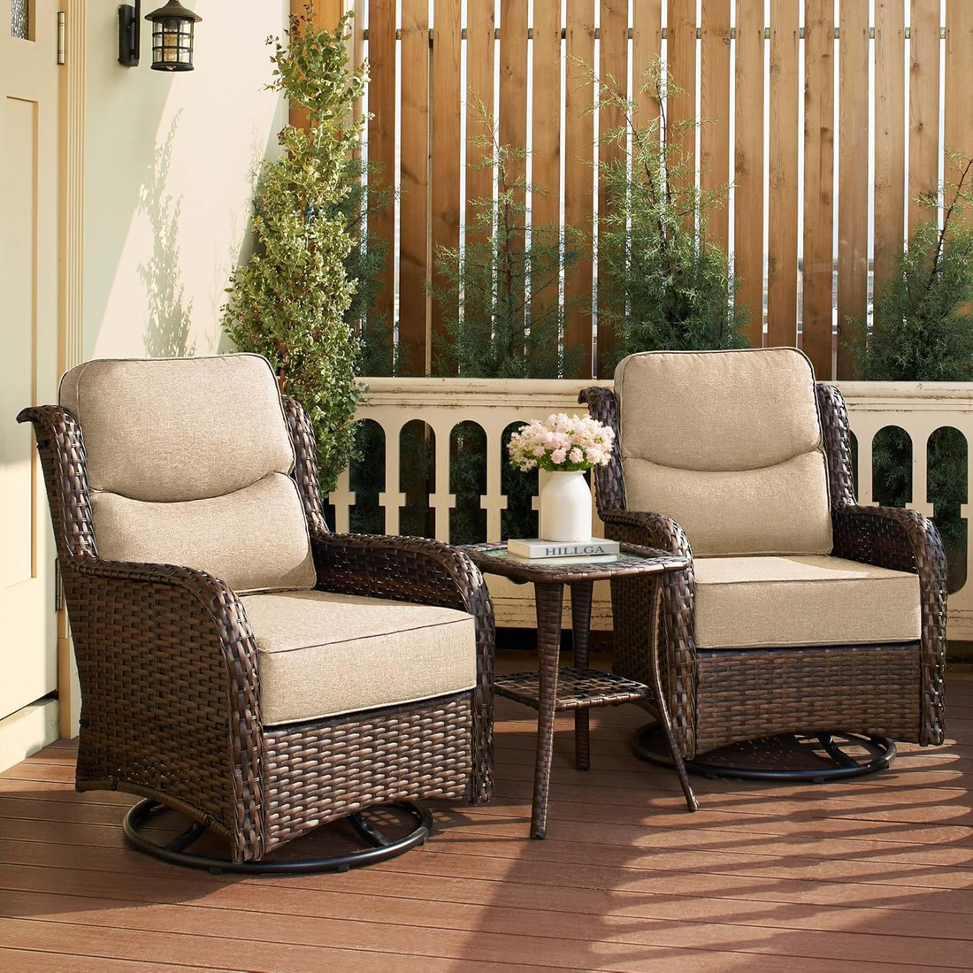 Two wicker chairs with beige cushions on a wooden deck with a small table and flowers.