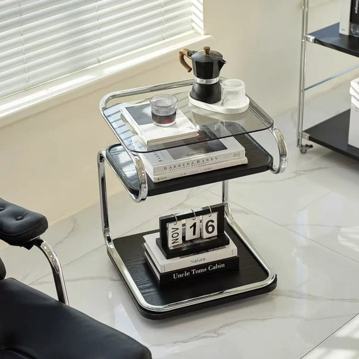 Two-tier glass table with books, a coffee maker, and a calendar on a marble floor.