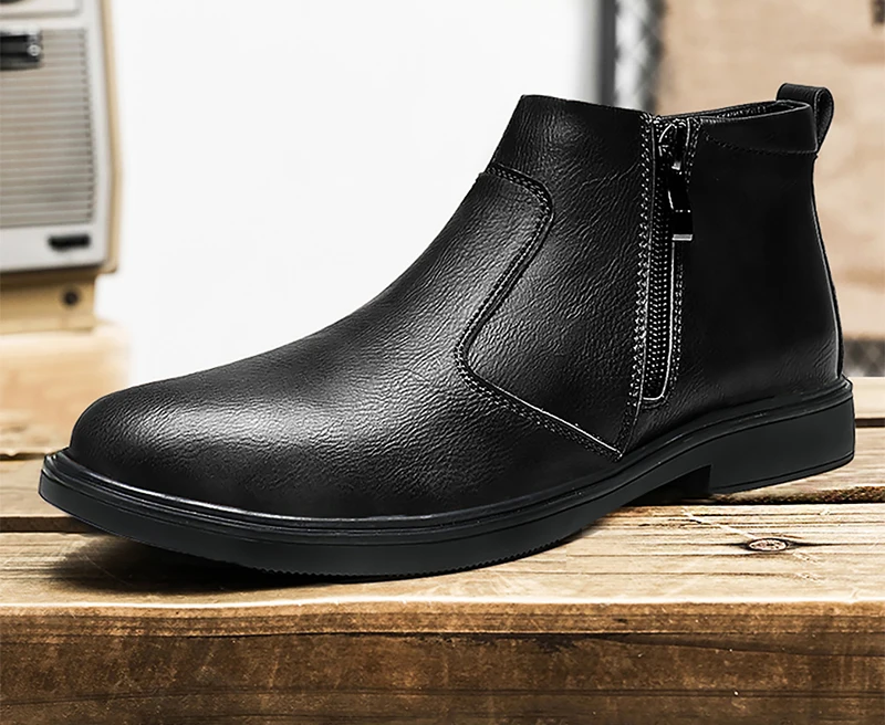 A single black leather ankle boot with a side zipper, displayed on a rustic wooden surface with a blurred indoor background.