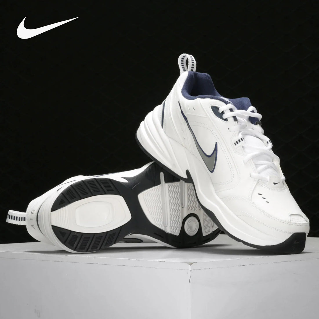 White and black Nike sneakers on a light gray surface with a black background