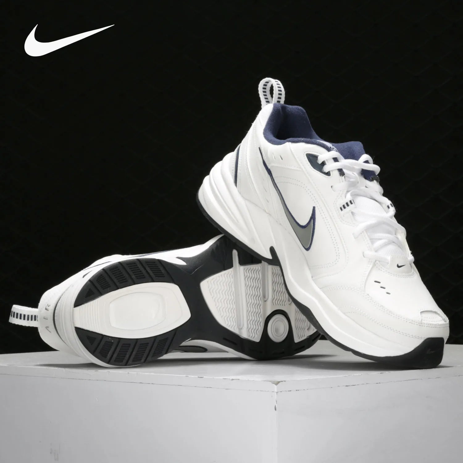 White and black Nike sneakers on a light gray surface with a black background