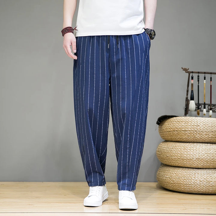 Person wearing blue striped pants with a white shirt in a room setting.