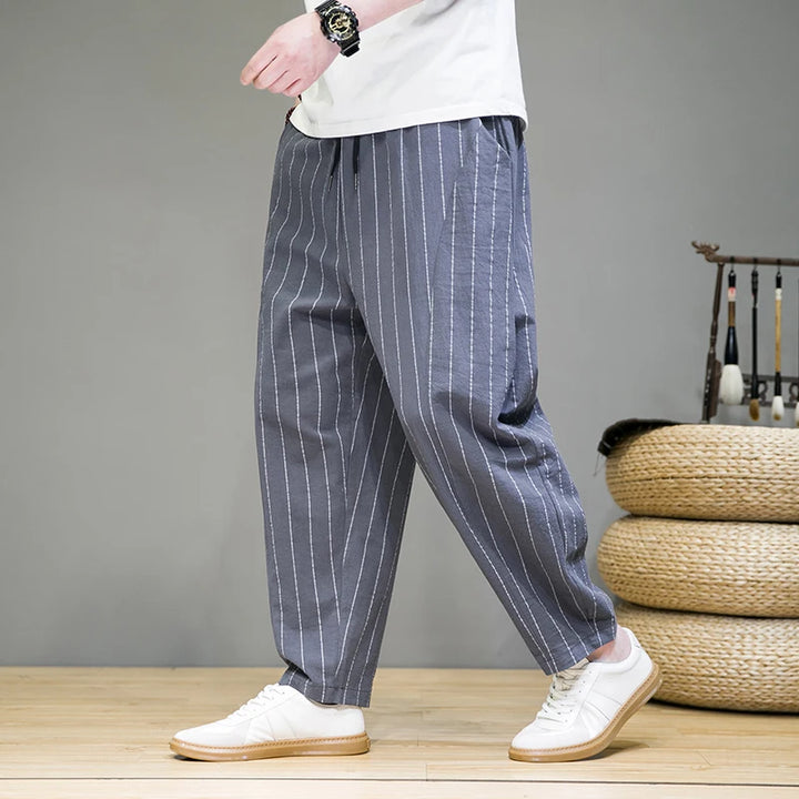 Person wearing blue pinstripe pants with a white shirt and white shoes on a wooden floor.