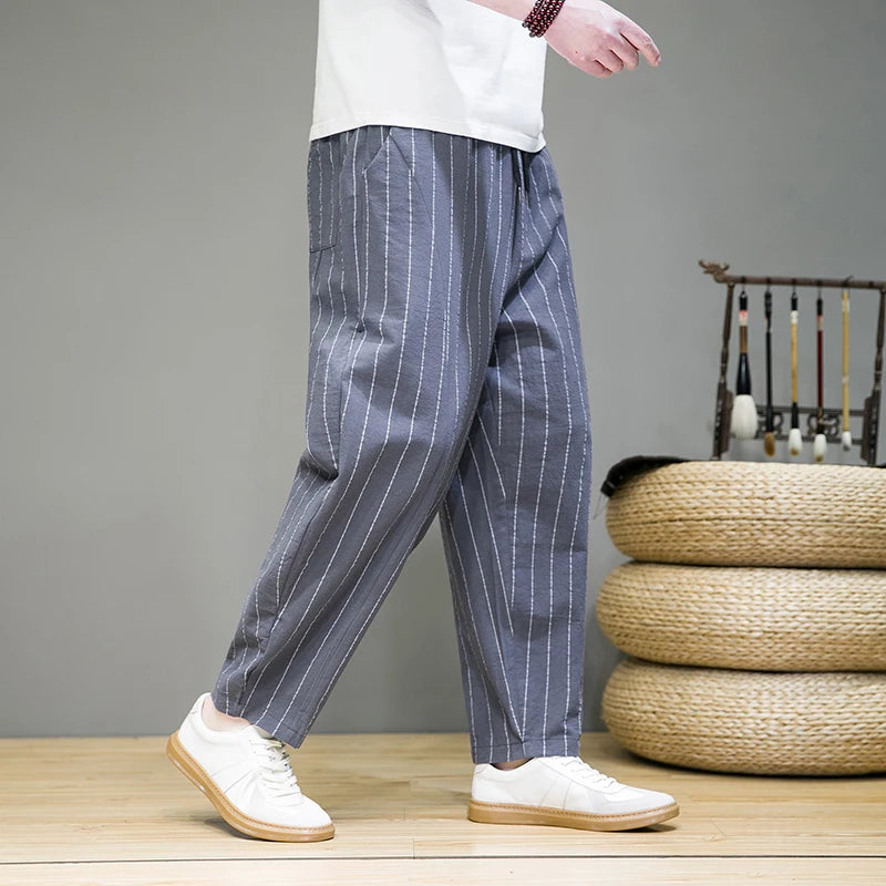 Person wearing blue striped pants and white shoes on a wooden floor with a gray wall and woven basket in the background.